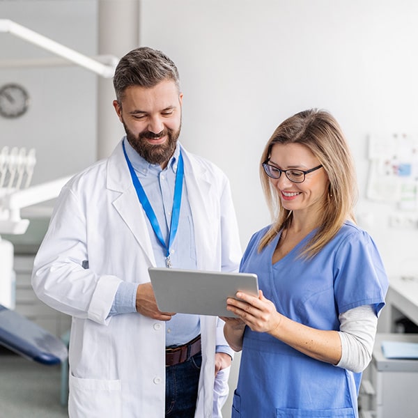 A dentist and dental assistant reviewing web pricing.